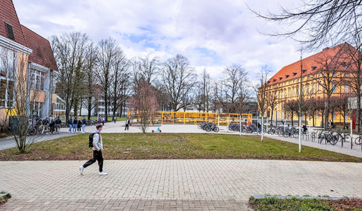 Mehrere Gebäude mit einem Platz und Menschen davor