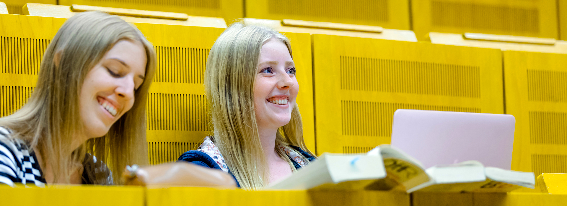 Zwei Studentinnen im Hörsaal mit Gesetzbüchern